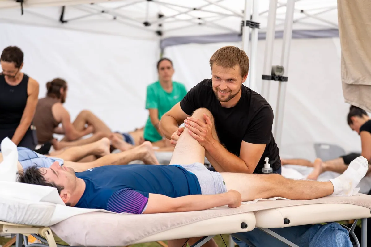 Massage sportif d'une jambe dans un village récupération sur un triathlon